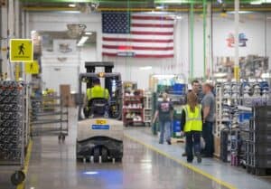 Manufacturing Institute warehouse with forklift and workers in safety vests.