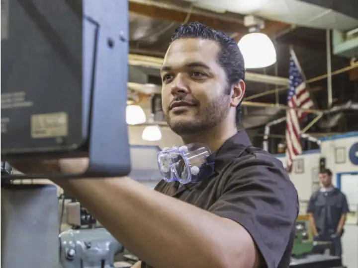 High-tech manufacturing worker using a computer in a factory setting.